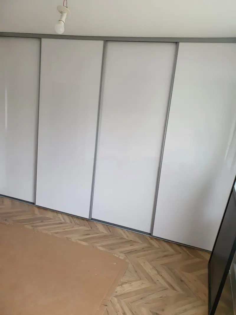 Placard à portes coulissantes blanches posé sur un parquet chevron