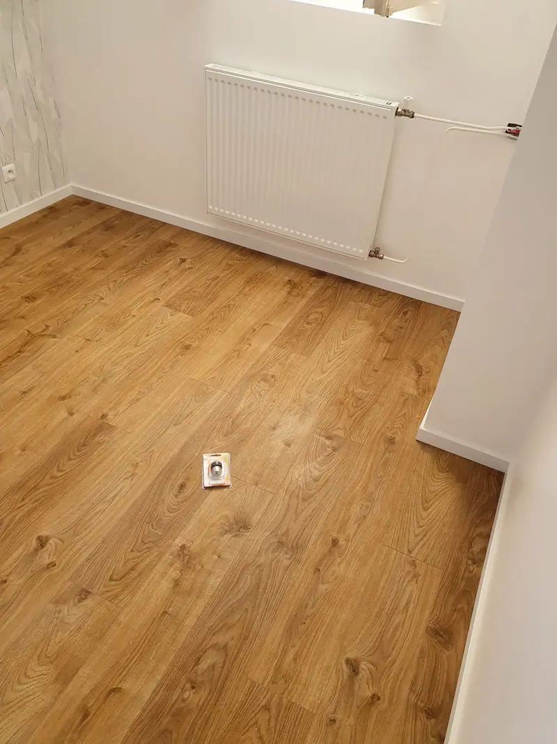Chambre repeinte en blanc avec sol stratifié et radiateur