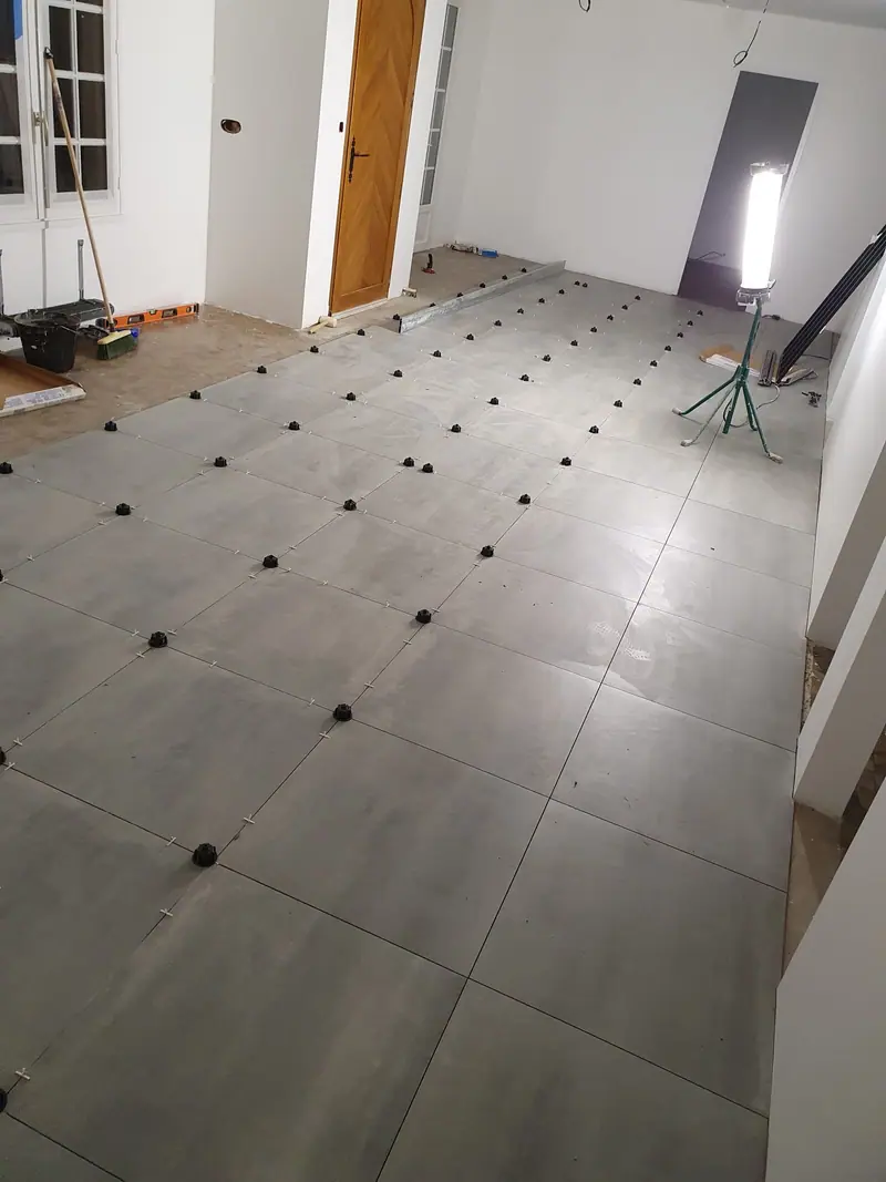 Carrelage grand format en cours de pose sur un plateau de bureaux