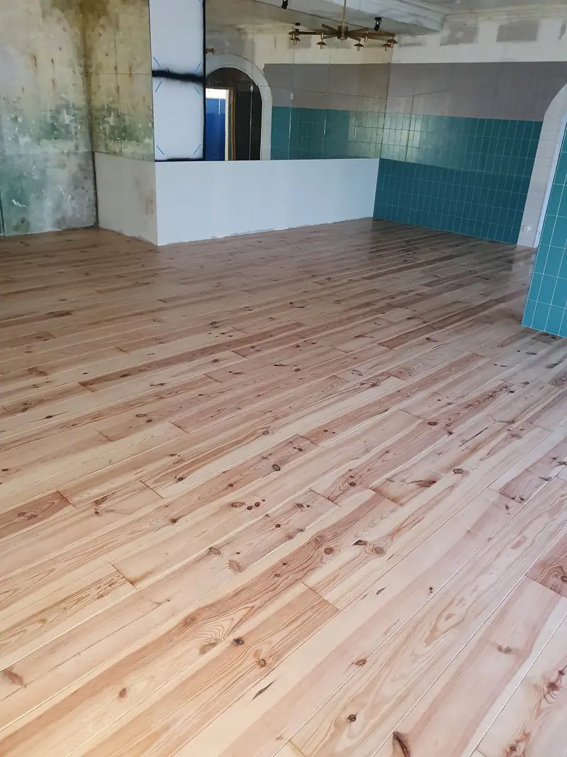 Vue d'ensemble du plancher en pin massif dans le local rénové