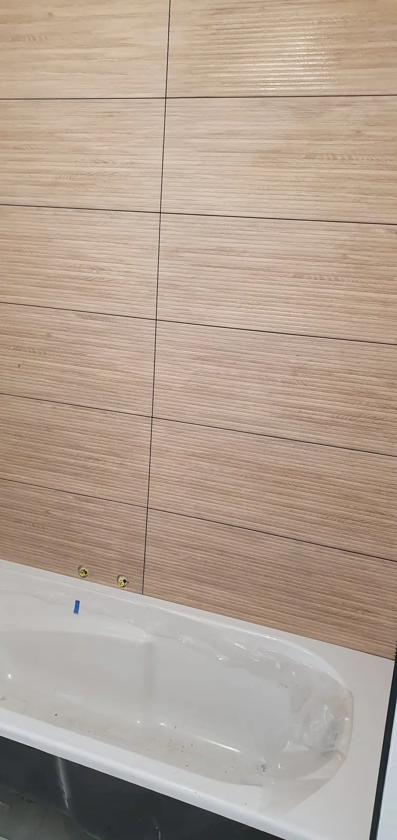 Baignoire installée devant un mur en faïence effet bois
